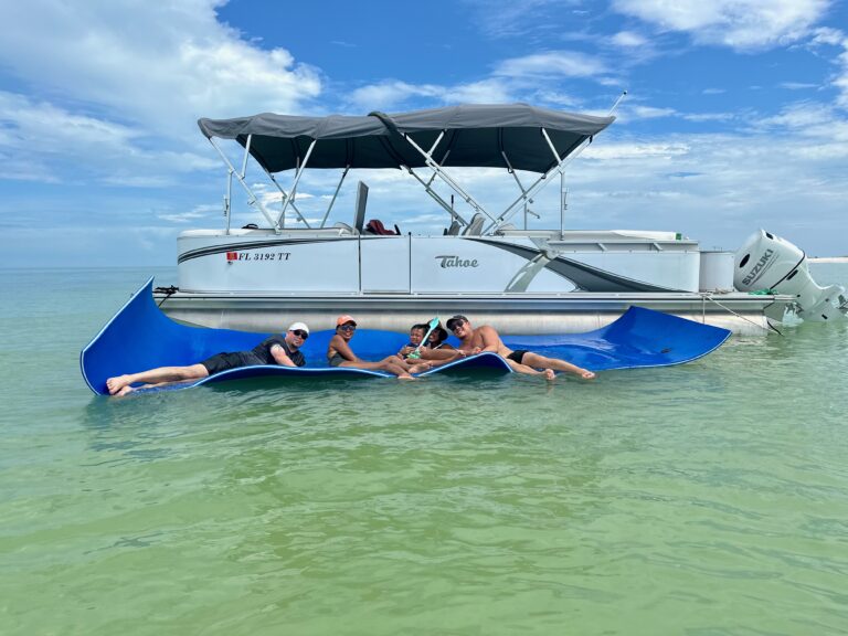 Family laying on float mat in front of white Pontoon boat