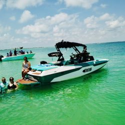 Axis wakeboat with family sitting at end of boat and in the water